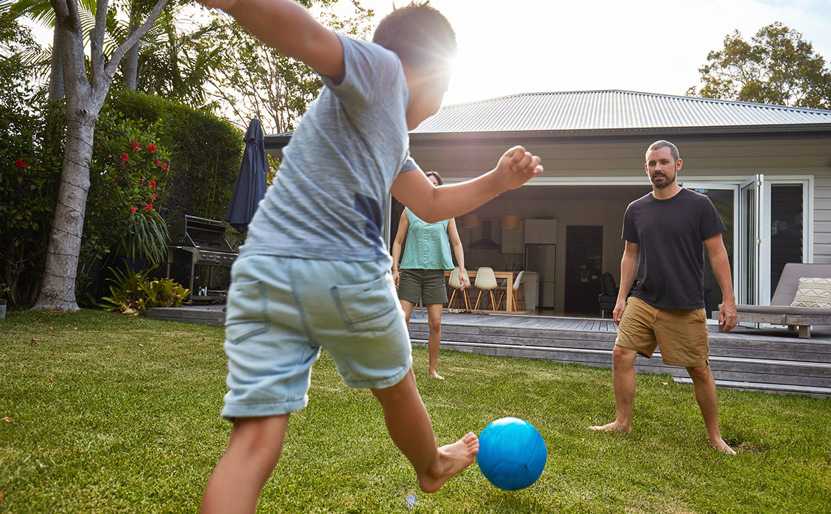 Parents and son playing soccer in the backyard