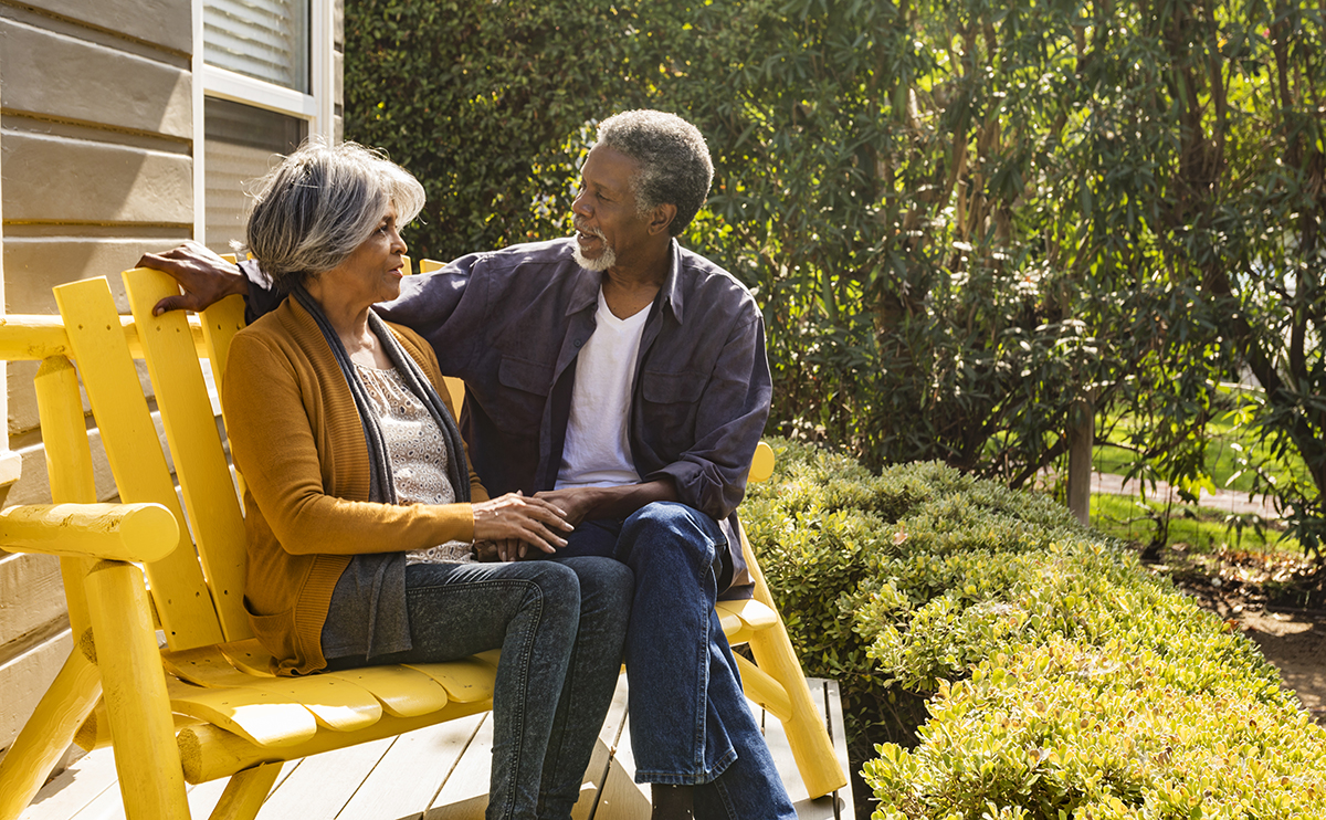 Elderly African American couple sitting outside in bright yellow chairs
