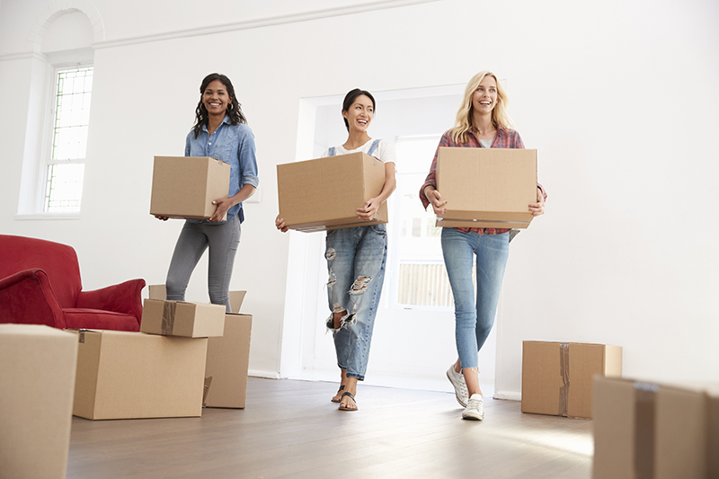 Three attractive young girls moving boxes into apartment