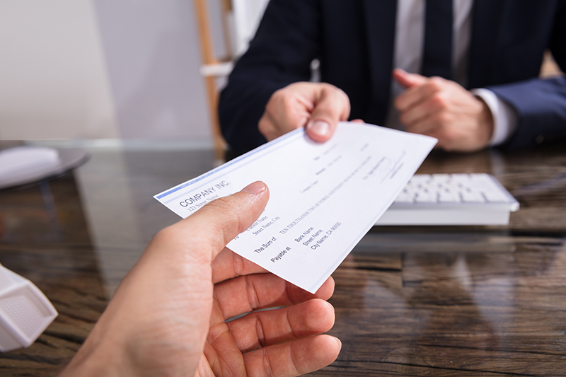 Man in business attire being handed a check from across the table