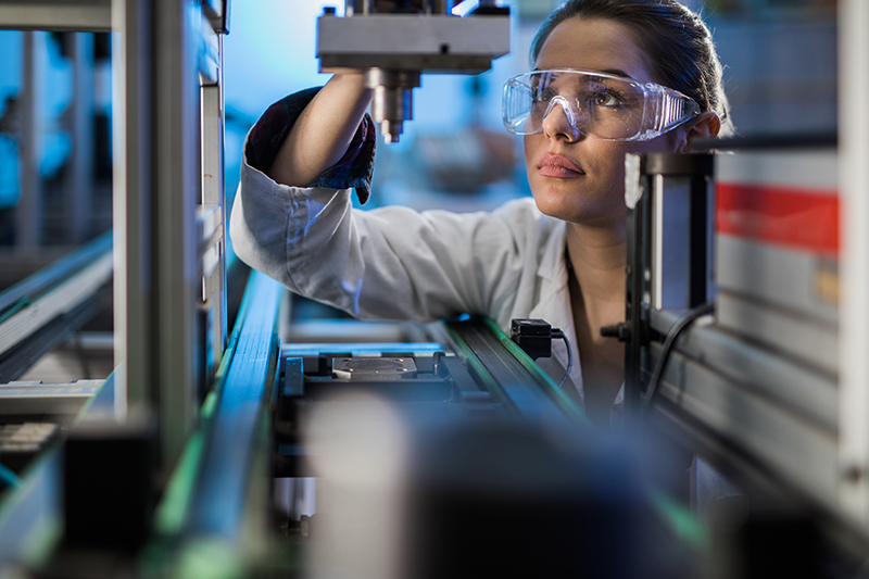 Milennial woman with safety glasses on performing science experiment