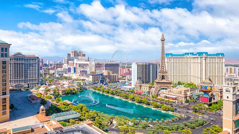 Aerial view of Las Vegas strip in Nevada mid-day, with fountain containing crystal blue water and Eiffel Tower in the forefront