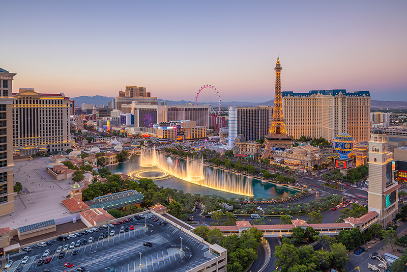 Aerial view of Las Vegas strip in Nevada in the early evening, with vibrantly colored fountain and the Eiffel Tower with-in the forefront.