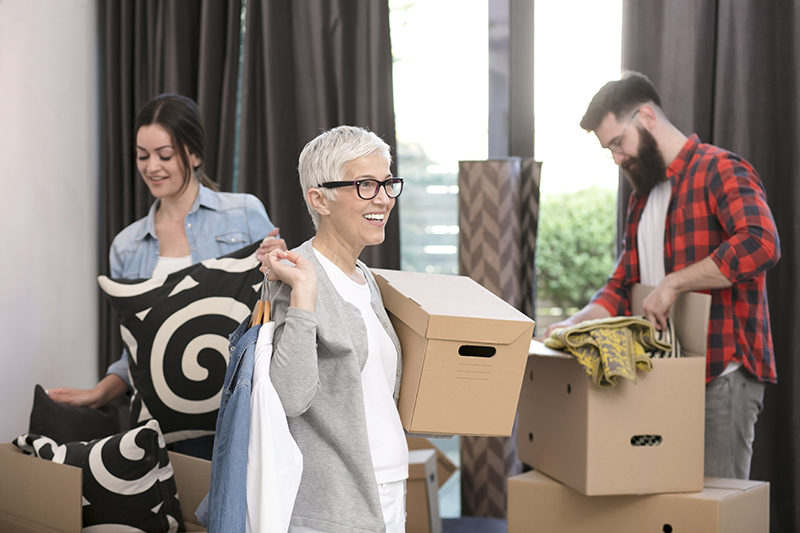 Young adults moving boxes and clothing into newly purchased home