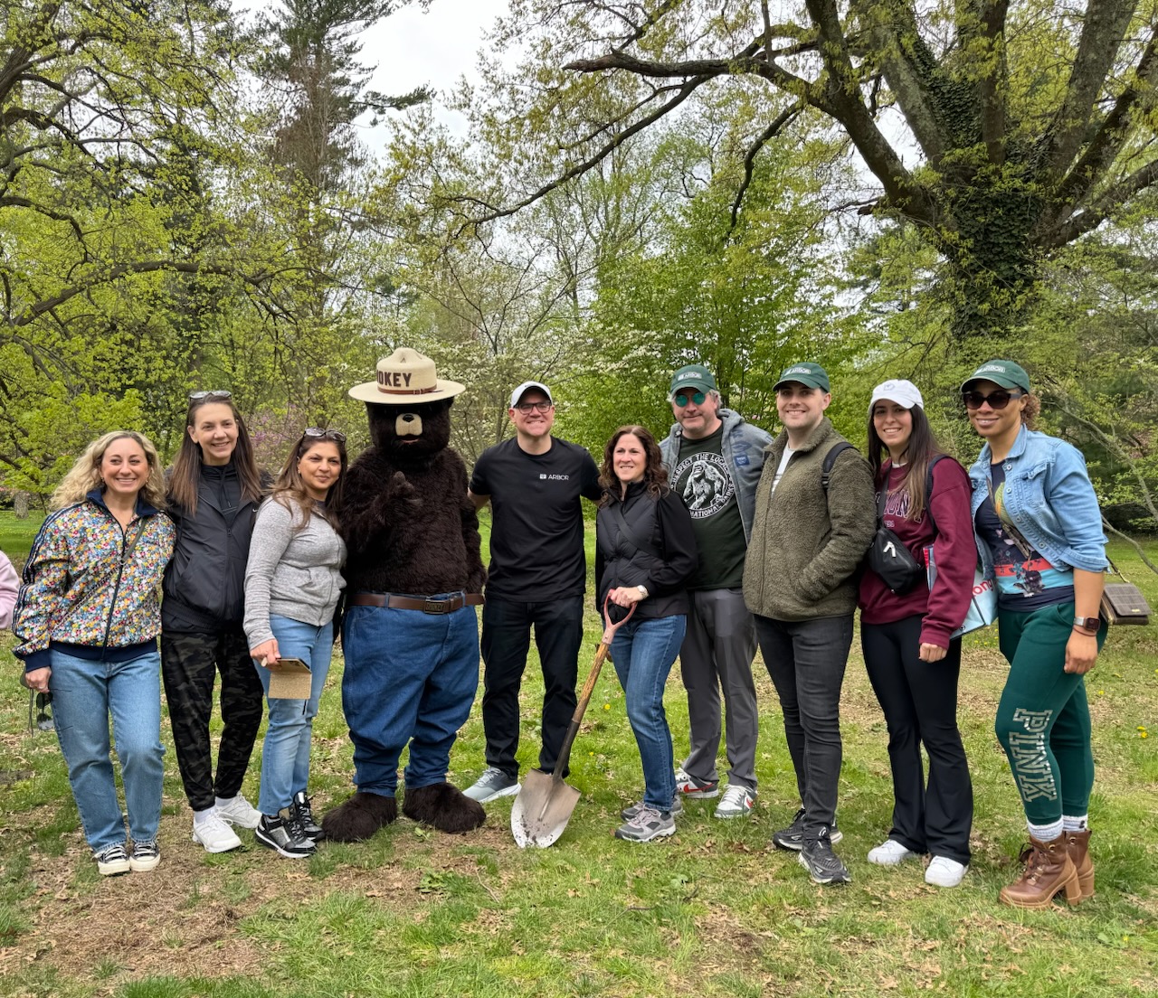 A group photo of Arbor employees doing tree plantings with Smokey Bear at Planting Fields Arboretum State Park.